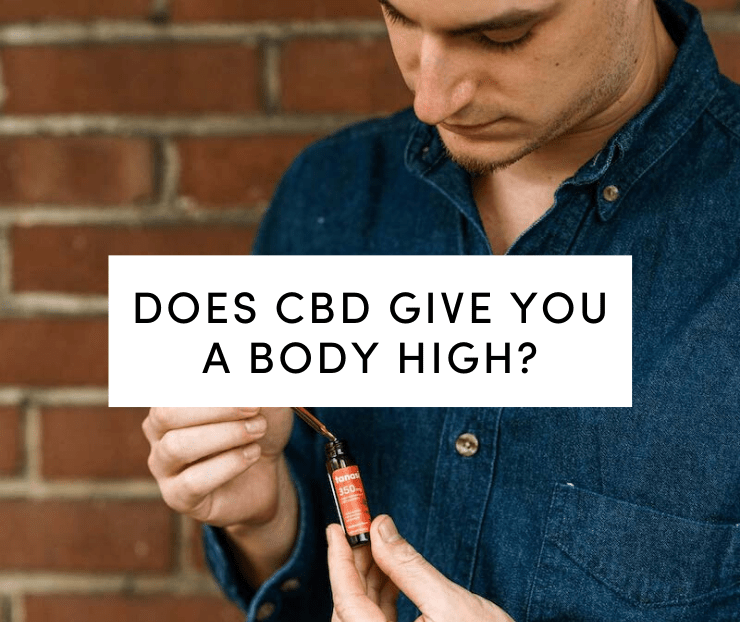 Man in blue shirt holding CBD tincture against brick wall