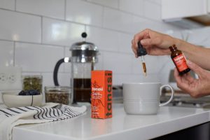 Hand using CBD tincture dropper for morning coffee