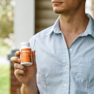 Man in blue shirt holding Tanasi CBD capsules