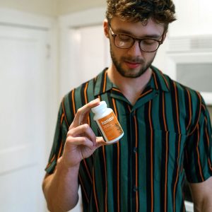 cbd and grapefruit: man in green shirt holding cbd capsules