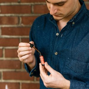 man in blue shirt holding tanasi cbd tincture